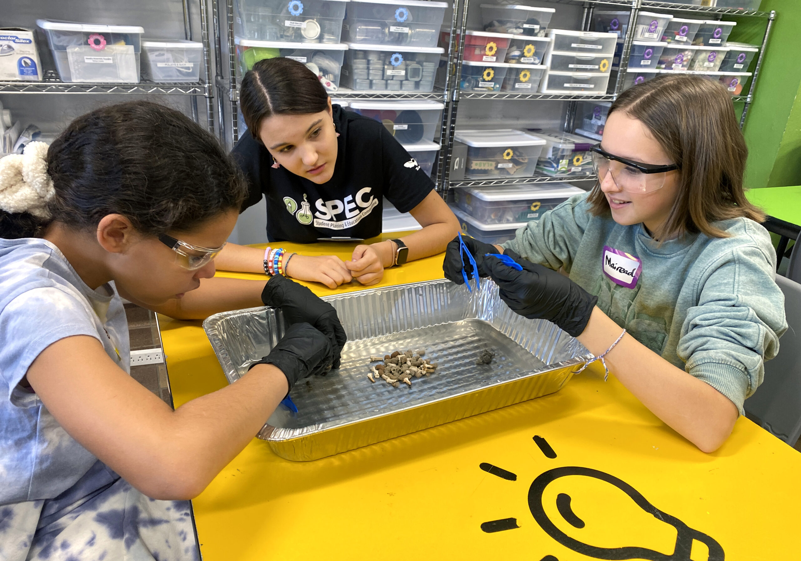 Zoe and campers SPEC instructor Zoe helps two students dissect owl pellets